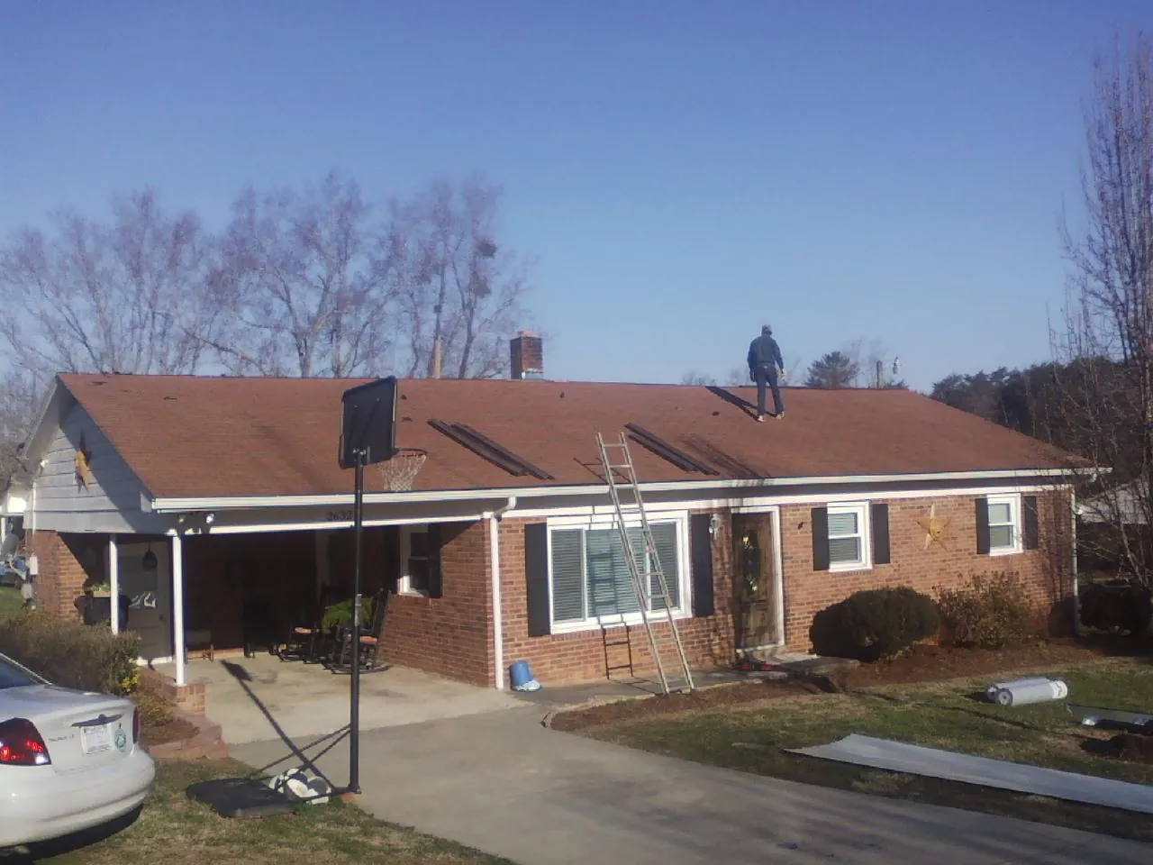 Roofer stripping a shingle roof on a brick ranch before metal panels in Canton